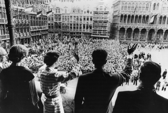 From the balcony of the Brussels City Hall, King Baudouin and Queen Fabiola greet the Belgian people with one heart as the crowd cheers.